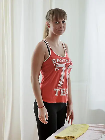 Young woman comes to massage and takes off baseball fan tank top