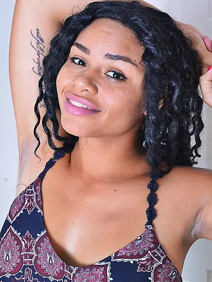 Black slut undresses looking into the camera and exposing her pu