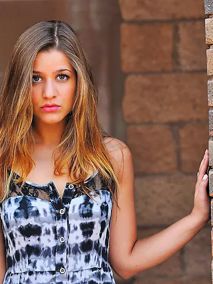 Kinky teen in long dress Teddi Rae is sitting on the bench showi