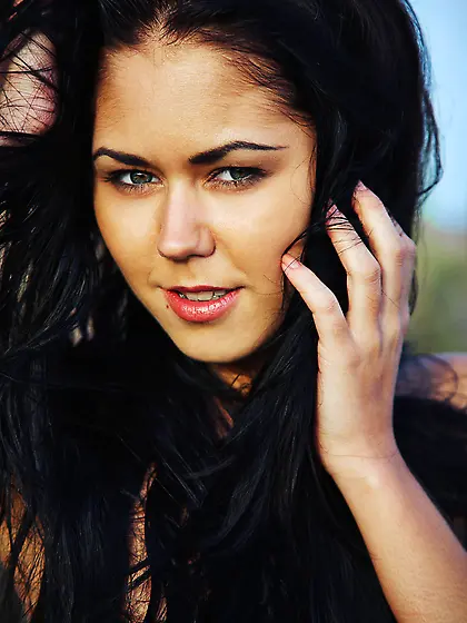 Tanned brunette with blue eyes posing naked in a middle of a fie