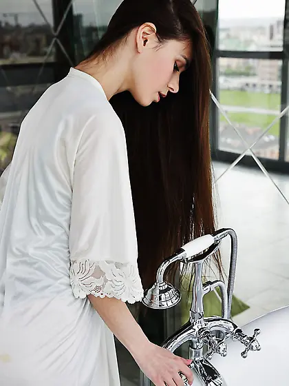 Horny young woman gets naked into the bathtub to relax after jou