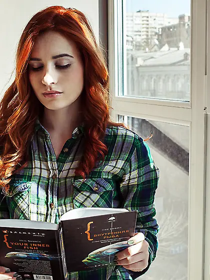 Redhead reads a book,  takes off her plaid shirt and grey lingeri